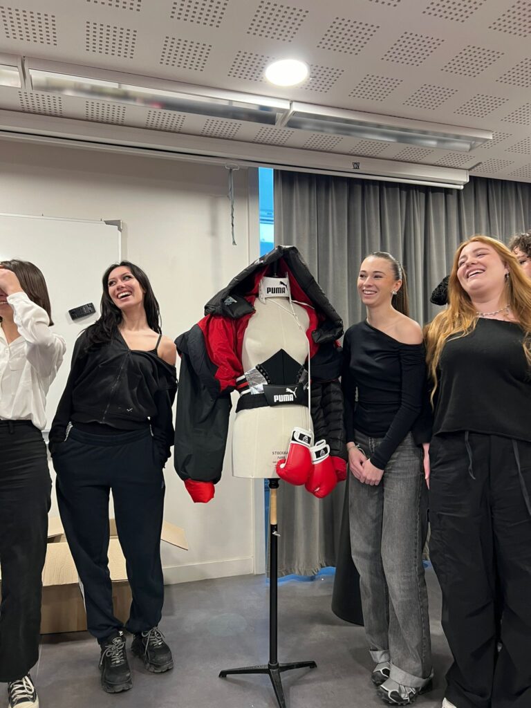 Étudiantes souriantes présentant un mannequin habillé avec des vêtements défectueux qu'elles ont retouchés pour leur donner une seconde vie.